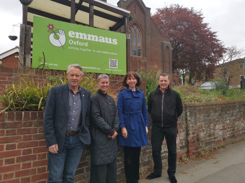 Andrew Morgan Giles, Chair of Trustees at Emmaus Oxford; Charlotte Talbott, Chief Executive of Emmaus UK; Anneliese Dodds, Oxford East MP; and Eddie Blaze, Chief Executive stood in front of a green sign which says "Emmaus Oxford"