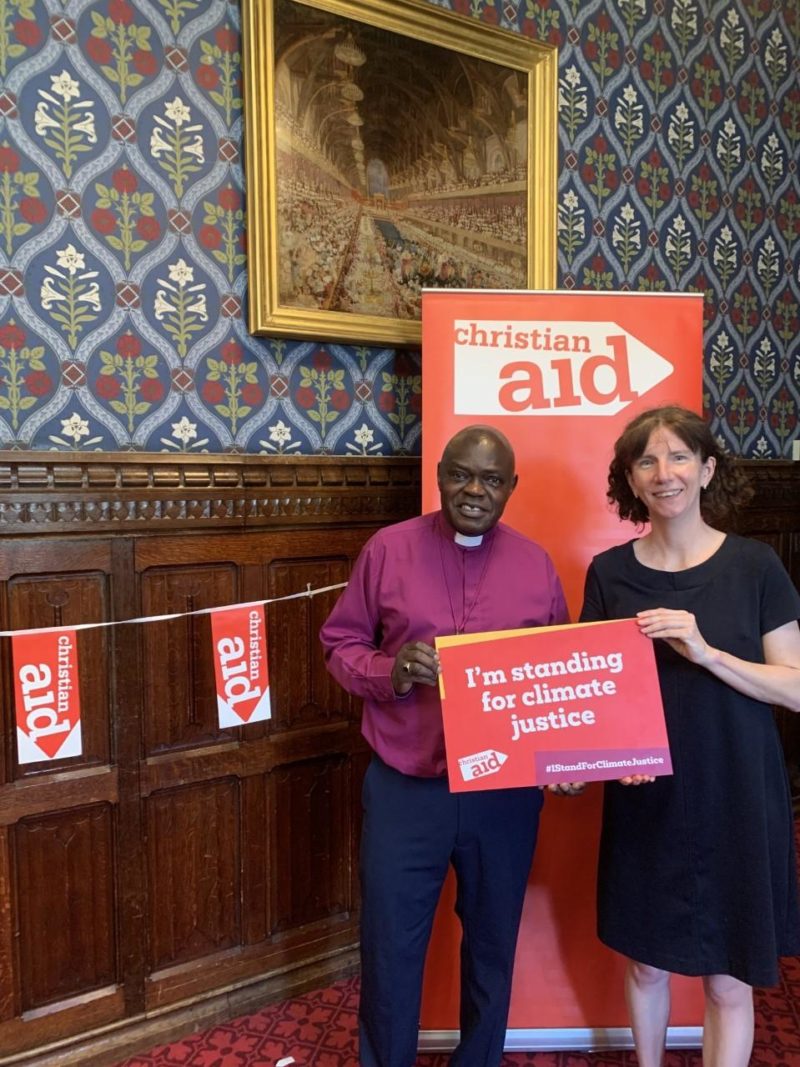 Dr John Sentamu and Anneliese Dodds MP in front of a red banner which has 